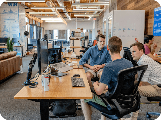 Group of people sitting on chairs in front of a computer